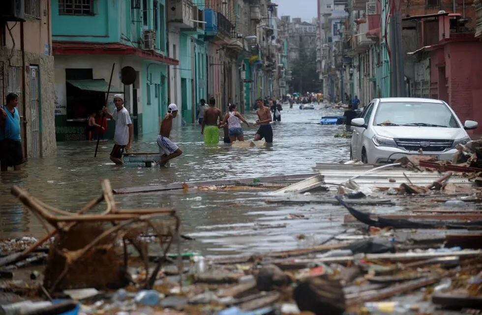 Cubans wade through a flooded street in Havana, on September 10, 2017.\nDeadly Hurricane Irma battered central Cuba on Saturday, knocking down power lines, uprooting trees and ripping the roofs off homes as it headed towards Florida. Authorities said they had evacuated more than a million people as a precaution, including about 4,000 in the capital.\n / AFP PHOTO / YAMIL LAGE