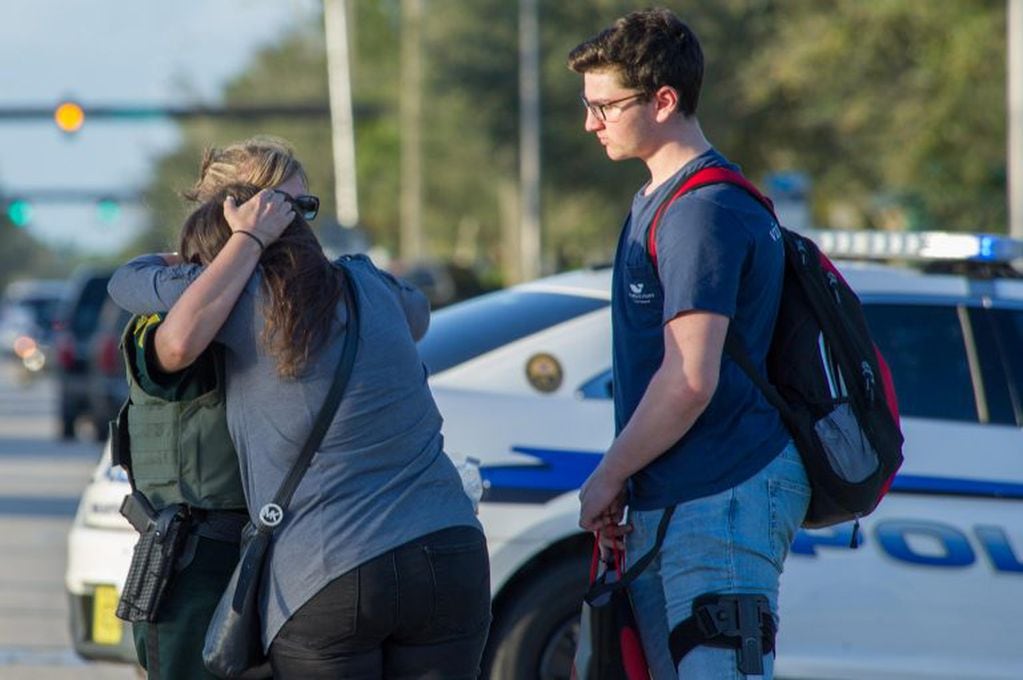 -FOTODELDIA- PAR01. PARKLAND (ESTADOS UNIDOS), 14/02/2017.- Una oficial de policía consuela a una mujer tras el tiroteo registrado hoy, miércoles 14 de febrero de 2018, en la escuela secundaria Marjory Stoneman Douglas de la ciudad de Parkland, en el sureste de Florida (Estados Unidos). Al menos 17 personas murieron hoy en Florida en un nuevo tiroteo ocurrido en una escuela en Estados Unidos, el decimoctavo en lo que va de año en centros educativos del país, en una masacre que se atribuye al exalumno de origen hispano Nikolas Cruz. EFE/GIORGIO VIERA