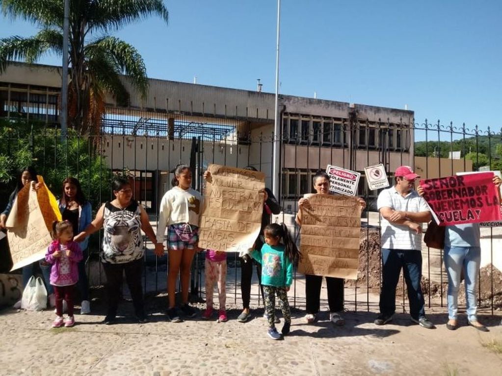 Algunos de los participantes en  el abrazo simbólico a la escuela ubicada en el barrio Santa Rosa, con carteles que explican sus reclamos.