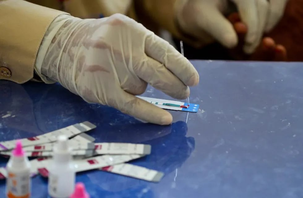 In this image taken on May 8, 2019, a Pakistani doctor examines the blood sample from a woman for a HIV test at a state-run hospital in Rato Dero in the district of Larkana of the southern Sindh province. - Parents nervously watch over their children as they jostle in line to be tested for HIV in a village near Pakistan’s Larkana amid a sudden outbreak among its young who have allegedly been infected by a doctor using a contaminated syringe. (Photo by RIZWAN TABASSUM / AFP) / TO GO WITH: Pakistan-health-HIV-children, SCENE by Ashraf KHAN