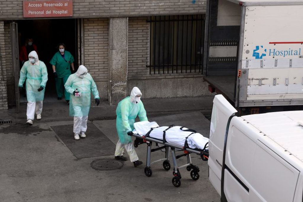 Trabajadores de la salud retiran el cuerpo de un fallecido por coronavirus en Italia (Foto: Oscar del Pozo/AFP)