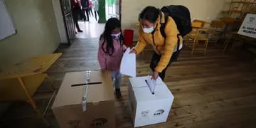 Una niña acompaña a una mujer a votar hoy en un centro electoral en Quito (Ecuador).