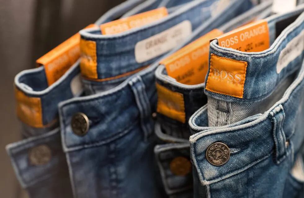 Tags sit stitched into the waistband of Boss Orange jeans as they hang on display at a Hugo Boss AG showroom in Metzingen, Germany, on Thursday, March 9, 2017. Hugo Boss AG, the ailing German clothier, said earnings may rise in 2017 as its turnaround takes shape after profit plummeted on weak sales in China and the U.S. last year. Photographer: Krisztian Bocsi/Bloomberg alemania  anuncio de la marca empresa Hugo Boss reestructuracion de la firma para aumentar las ventas caida de las ventas en el au00f1o 2016