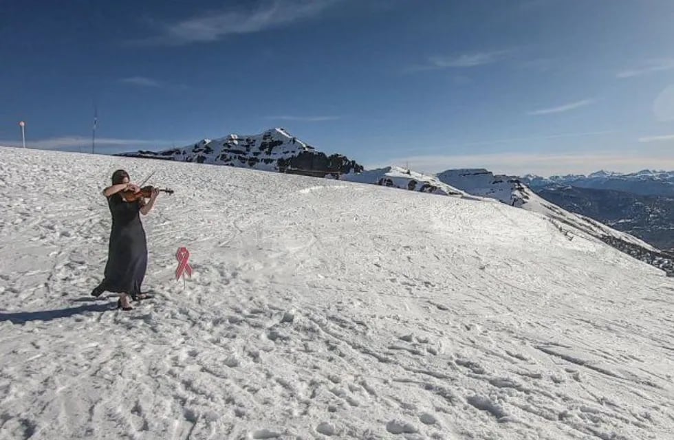 Tania Rubiolo tocando el violín en el cerro Teta para concientizar sobre el cáncer de mama.