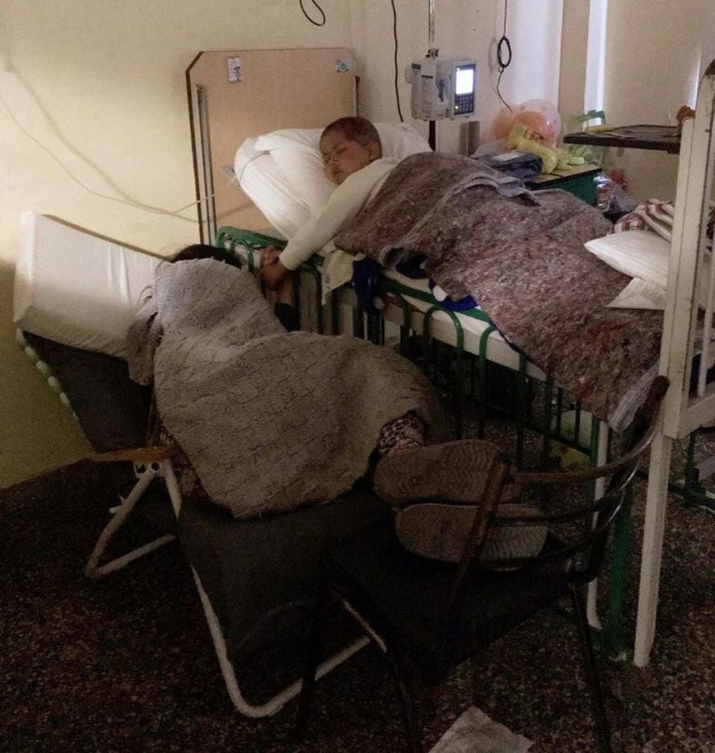 Thiago y su mamá, en la sala de oncología del Hospital de Niños dormidos y tomaditos de la mano. (Facebook Juan Pablo Rodríguez)