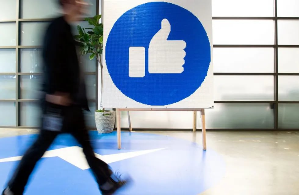 (FILES) In this file photo taken on October 23, 2019 a Facebook employee walks by a sign displaying the \