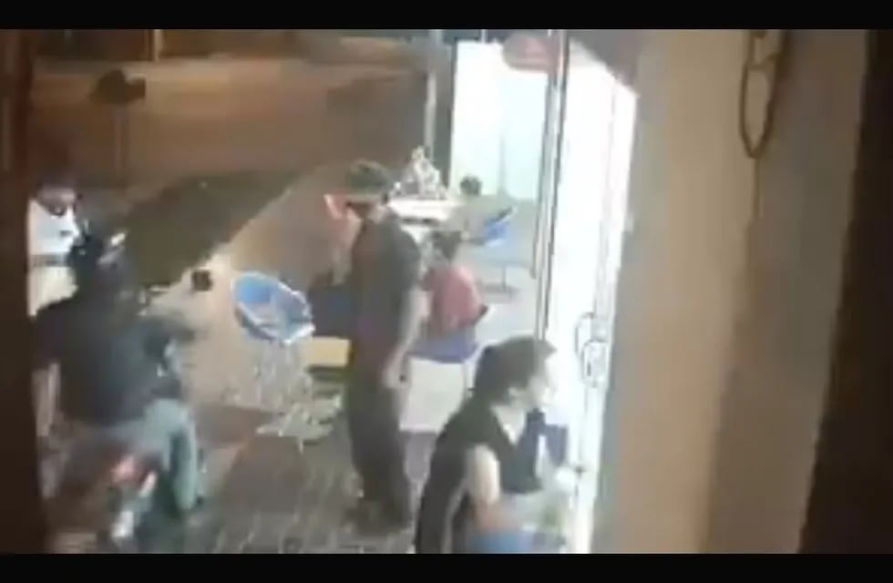 La inseguridad no da respiro a sufridos cordobeses como este cliente asaltado por un motochoro en la vereda de una heladería (imagen de video).