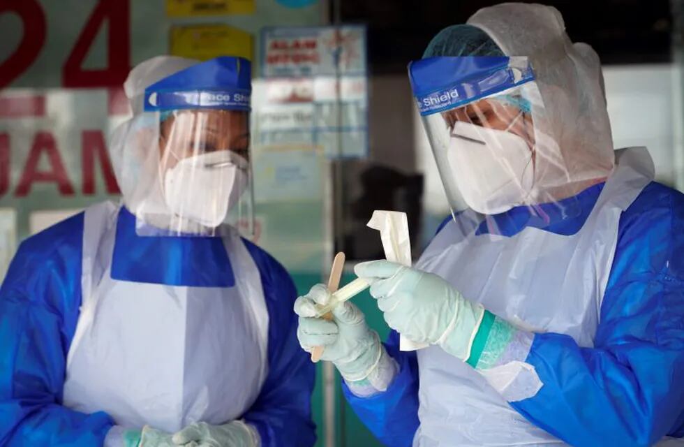 A clinic doctor checks sample for coronavirus testing after they collected it from a man on the outskirt of Kuala Lumpur, Malaysia, Tuesday, Oct. 6, 2020. The health ministry has warned that Malaysia is facing a new wave of virus cases as the outbreak has widened in recent days. New clusters have sprung up in many states amid increased travel to eastern Sabah state, a hotspot zone, for a state election last month. (AP Photo/Vincent Thian)
