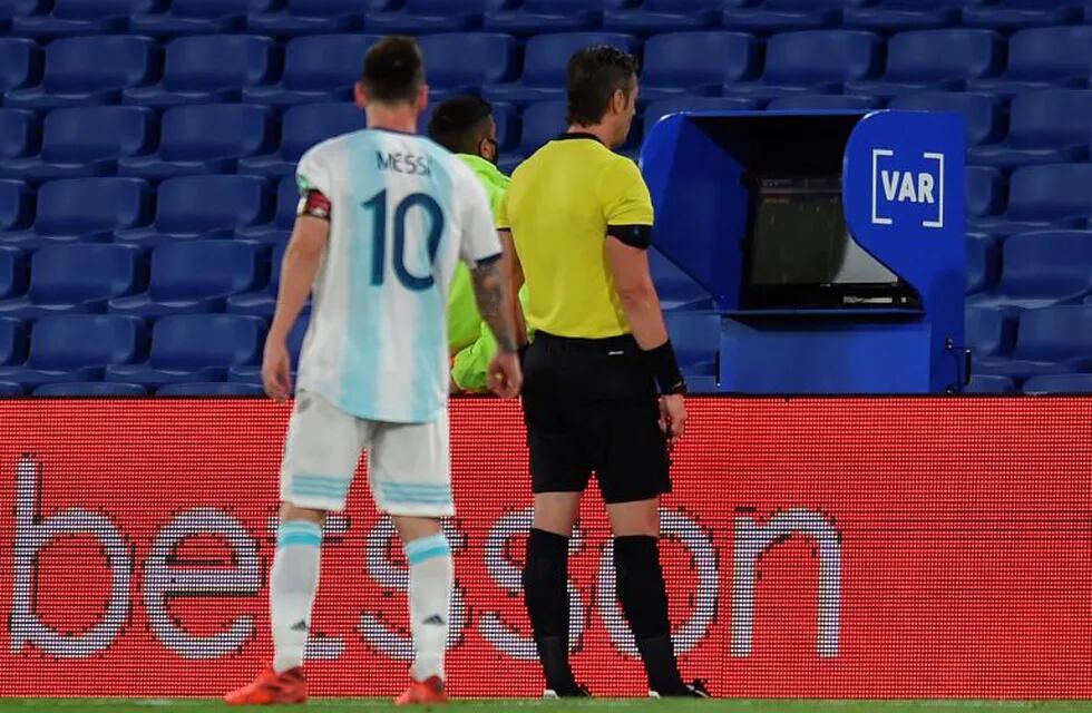Lionel Messi mira el VAR junto al árbitro brasileño Raphael Claus en el partido ante Paraguay por las Eliminatorias para Qatar 2022 (Marcelo Endelli / AFP)