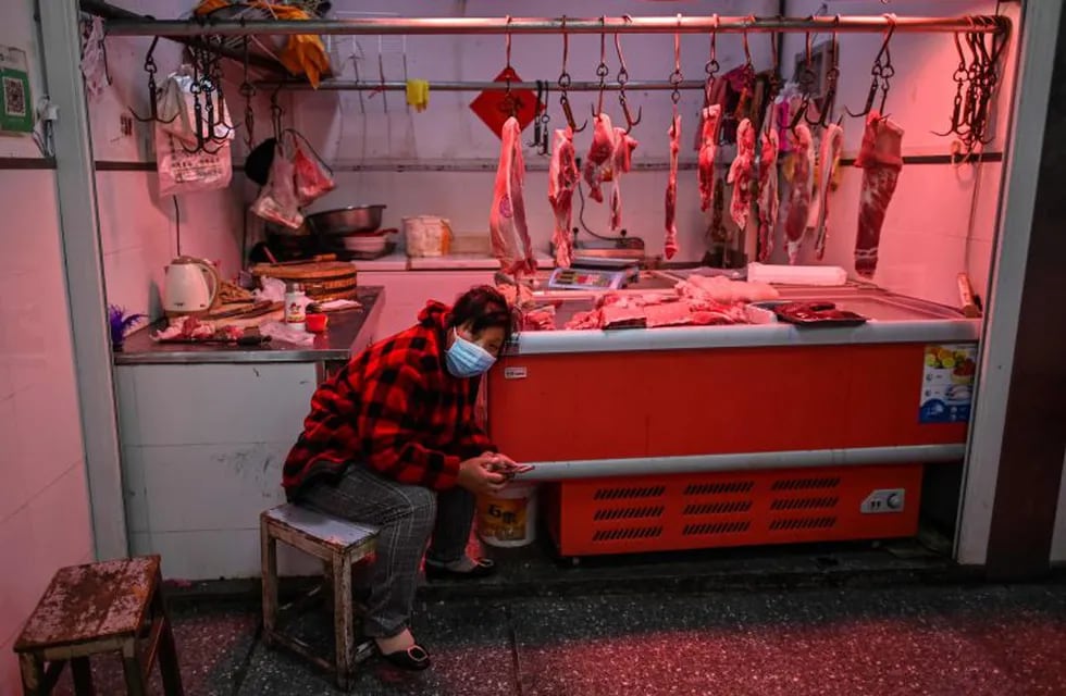 A meat vendor wearing a face mask waits for a customer at a market in Wuhan, on April 2, 2020. - Wuhan, the central Chinese city where the coronavirus first emerged last year, partly reopened on March 28 after more than two months of near total isolation for its population of 11 million. (Photo by Hector RETAMAL / AFP)