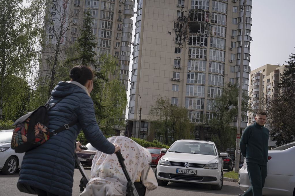 Gente pasa junto a un edificio de apartamentos dañado por restos de un dron derribado durante un ataque ruso por la noche. Los de este lunes, son las primeras ofensivas del Kremlin que se dan durante el día. Foto: AP / Andrew Kravchenko.