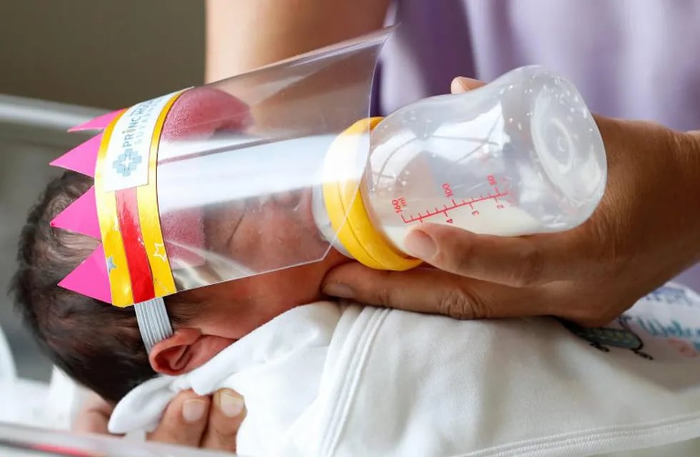 -FOTODELDÍA-RUN1096. SAMUT PRAKAN, 08/04/2020.- Un bebé recién nacido tailandés usa un protector facial para evitar el contacto con la enfermedad COVID-19 y el coronavirus mientras es alimentado con biberón por una enfermera, en el Hospital Princ Suvarnabhumi, en la provincia de Samut Prakan, Tailandia, 08 de abril de 2020. El hospital proporciona protectores faciales recién nacidos para prevenir la propagación continua de la enfermedad COVID-19 causada por el coronavirus SARS-CoV-2. EFE/EPA/RUNGROJ YONGRIT