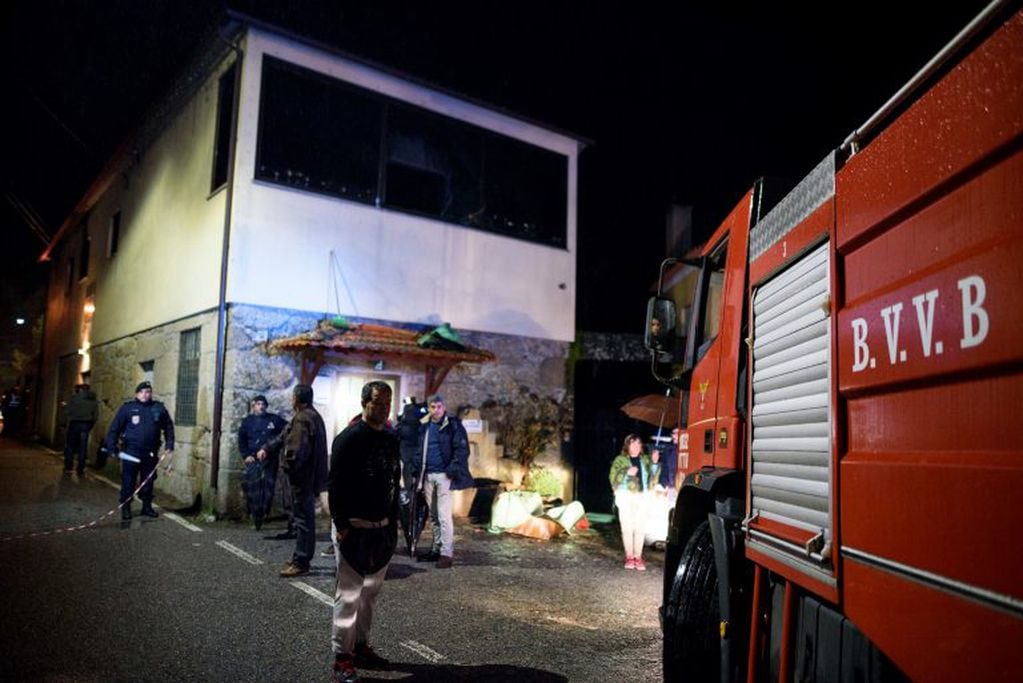 Policemen work outside the building, in the background, where a heater exploded killing people in the village of Vila Nova da Rainha, outside Tondela, northern Portugal, in the early hours of Sunday, Jan. 14 2018. A wood-burning stove exploded and started a fire late Saturday at the packed premises of a local residents' association in the north of Portugal, officials said. (AP Photo/Sergio Azenha)
