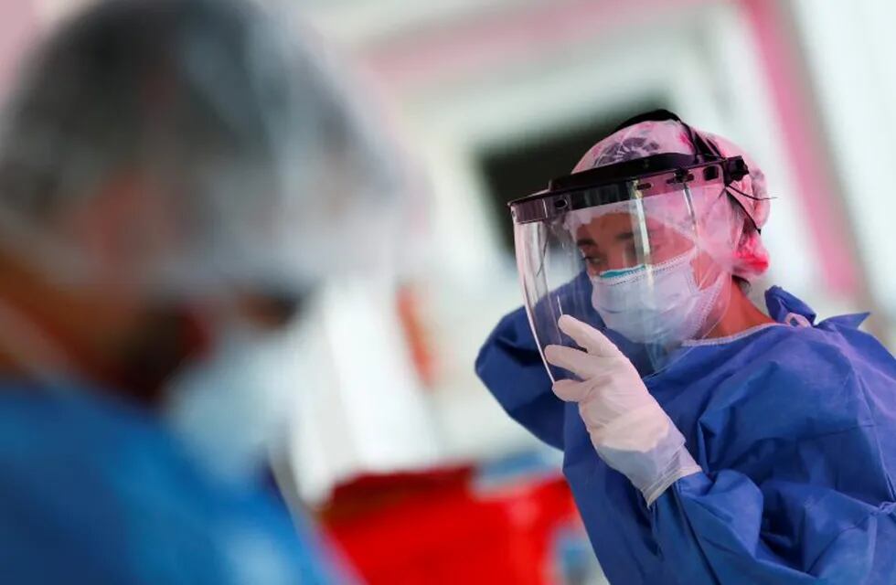 Kinesiologist Maria Luz Porra puts on a mask shield before checking patients suffering from the coronavirus disease (COVID-19) in an intensive care unit of an hospital, on the outskirts of Buenos Aires, Argentina October 16, 2020. Picture taken October 16, 2020. REUTERS/Agustin Marcarian  TERAPIA INTENSIVA CASOS DEL DIA