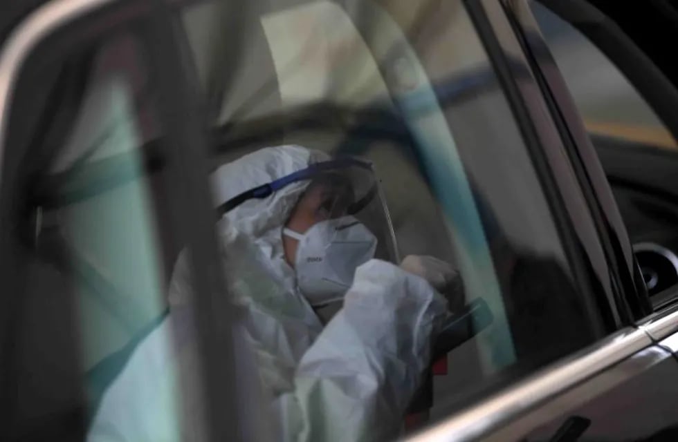 A Covid-19 tester reflects in a car window during the talk with a car driver before the driver takes a smear himself in a car testing station in Erkheim, southern Germany, on November 4, 2020, amid the new coronavirus COVID-19 pandemic. (Photo by Christof STACHE / AFP)