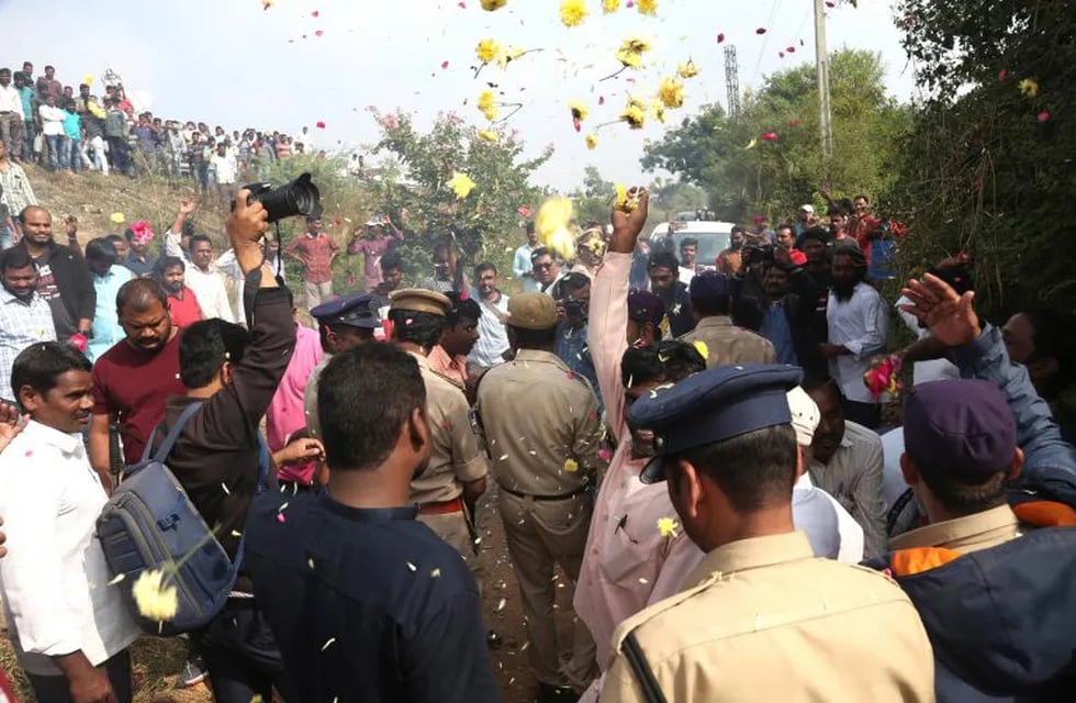 People throw flower petals on the Indian policemen guarding the area where rape accused were shot, in Shadnagar some 50 kilometers or 31 miles from  Hyderabad, India, Friday, Dec. 6, 2019. An Indian police official says four men accused of raping and killing a woman in southern India have been fatally shot by police. (AP Photo/Mahesh Kumar A.)