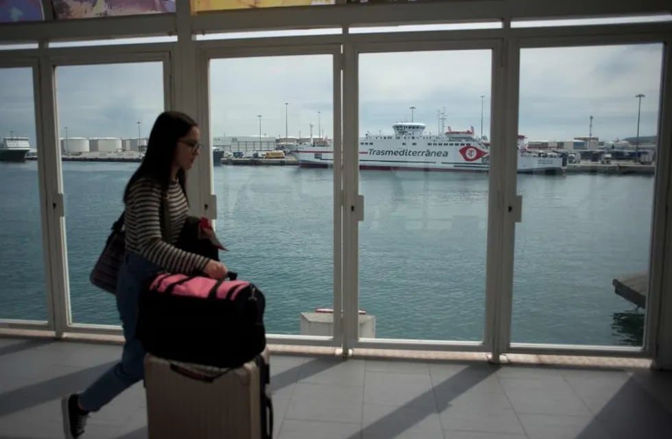 A woman pushes a suitcase at Algeciras harbour on March 13, 2020. - Morocco closed the border with Ceuta and Melilla, Spain's two North African enclaves to prevent the spread of the deadly coronavirus. After Italy, Spain is the worst-hit country in Europe, with officials taking numerous measures to try and halt the spread of the deadly virus, with schools shuttered across the country along with museums, theatres, gyms and sports facilities. (Photo by JORGE GUERRERO / AFP)