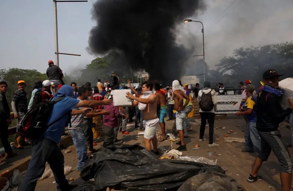Opposition supporters unload humanitarian aid from a truck that was sent on fire after clashes between opposition supporters and Venezuela's security forces at Francisco de Paula Santander bridge on the border line between Colombia and Venezuela as seen from Cucuta, Colombia, February 23, 2019. REUTERS/Marco Bello