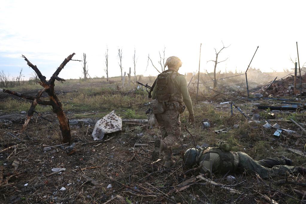 Un comandante de una unidad de la 3ra Brigada de Asalto que utiliza el nombre de Fedia pasa junto al cuerpo de un soldado ruso muerto en Andriivka, en la región de Donetsk, Ucrania, el sábado 16 de septiembre de 2023. (AP Foto/Alex Babenko)