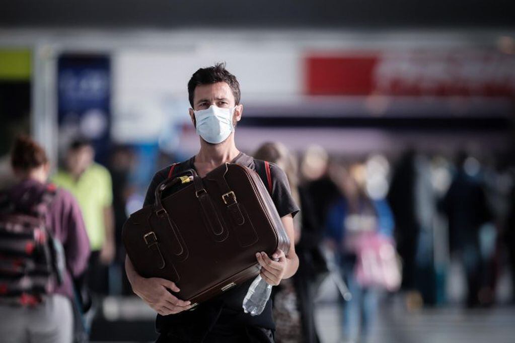 Pasajeros usan cubrebocas para protegerse del coronavirus mientras transitan por el Aeropuerto Internacional de Ezeiza, en marzo (EFE/Juan Ignacio Roncoroni)
