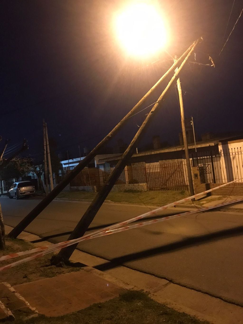 Dos postes de luz fueron volteados por el viento y quedaron sostenidos por cables.