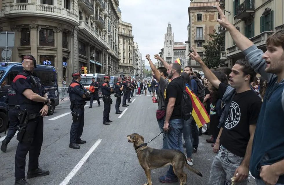 Mossos d'Esquadra permanecen en guardia ante un grupo de jóvenes que protestan frente a una comisaría de la Policía Nacional. (EFE).