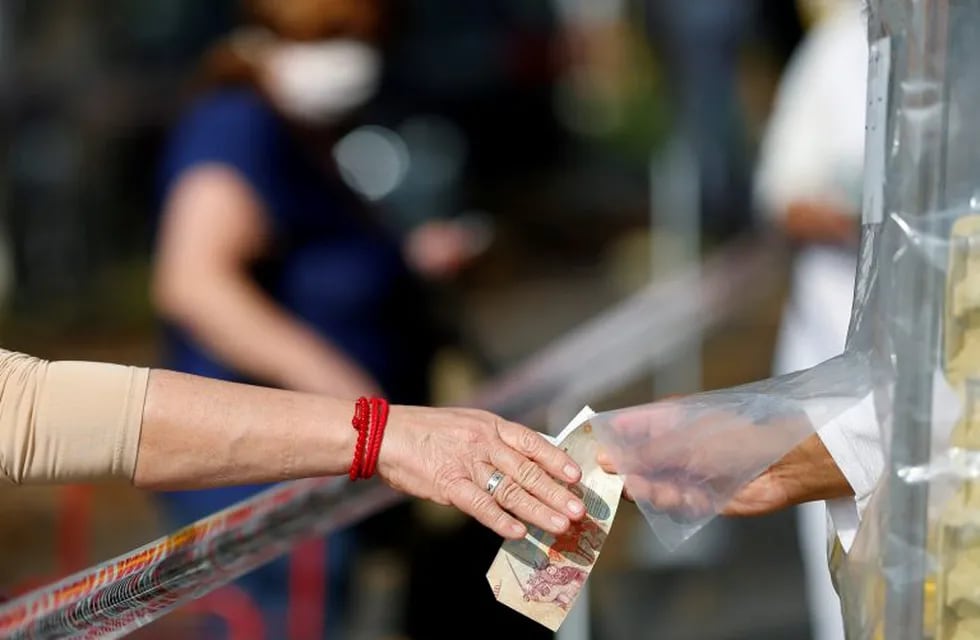 A woman pays in a shop protected with a tape as a preventive measure against the spread of the coronavirus disease (COVID-19) at a street market, in Buenos Aires, Argentina May 20, 2020. REUTERS/Agustin Marcarian