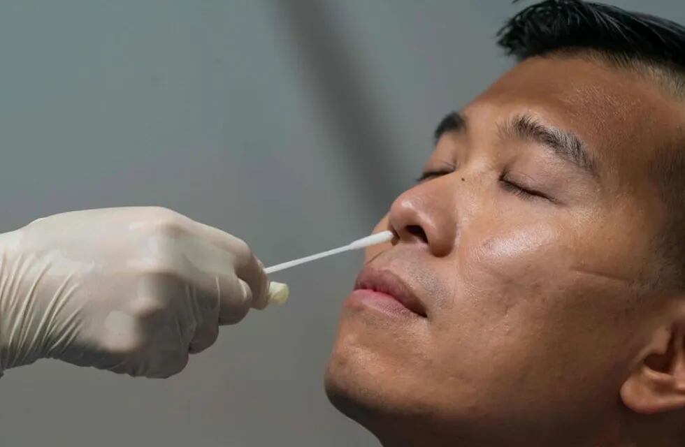 A swab sample is collected from a man at a makeshift testing site to for COVID-19 coronavirus infections at the Queen Elizabeth Stadium in Hong Kong on September 1, 2020. - Hong Kong launched a mass coronavirus testing scheme on September 1, but calls for millions to take up the offer have been undermined by deep distrust of the government following China's crushing of the city's democracy movement. (Photo by Anthony Kwan / POOL / AFP)