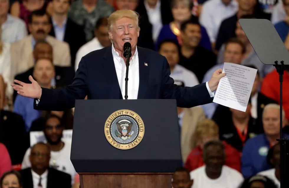 President Donald Trump gestures as he holds up a piece of paper on the presidential powers on immigration during a campaign rally Saturday, Feb. 18, 2017, at Orlando-Melbourne International Airport, in Melbourne, Fla. (AP Photo/Chris O'Meara)