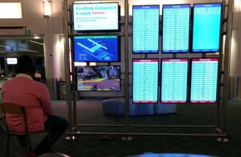 El hombre jugando a la PlayStation en un monitor donde se muestran los vuelos. (Twitter)