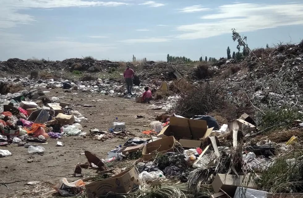 Una madre y sus hijos revolviendo la basura.