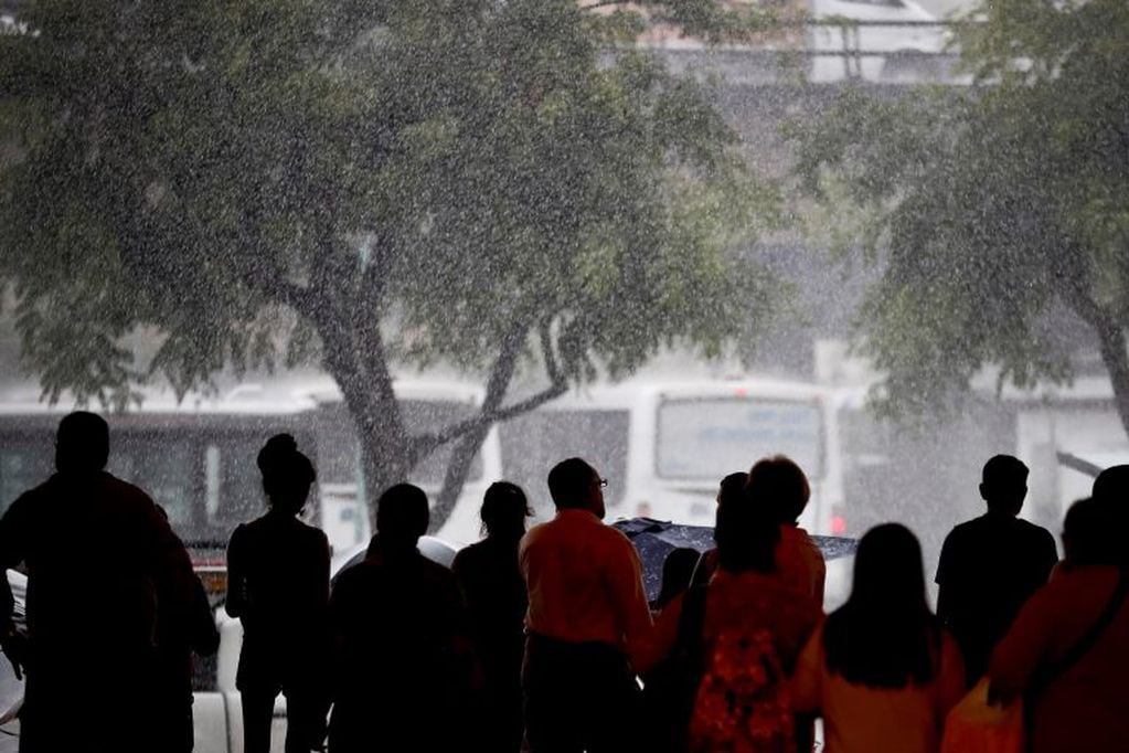 Personas esperan durante un intensa lluvia. (EFE/Juan Ignacio Roncoroni)