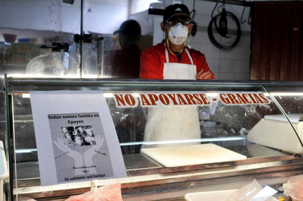 Un carnicero lleva puesta una máscara sanitaria por el brote de hantavirus. A su lado el cartel dice: "Todos somos familias en Epuyen. Se solidario: usá barbijo!".  (AP Photo/Gustavo Zaninelli).