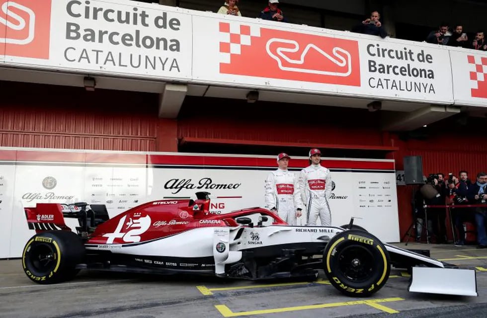 Drivers Kimi Raikkonen of Finland, left, and Antonio Giovinazzi of Italy, right, pose for photos with the new Alfa Romeo F1 car during a presentation of the new livery at the Barcelona Catalunya racetrack in Montmelo, outside Barcelona, Spain, Monday, Feb.18, 2019. (AP Photo/Manu Fernandez)