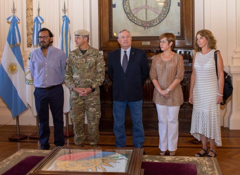 El ministro Perassi, junto a la diputada Burgos y el mayor Cristóbal, encabezando el acto en el Salón de la Bandera de la Casa de Gobierno.