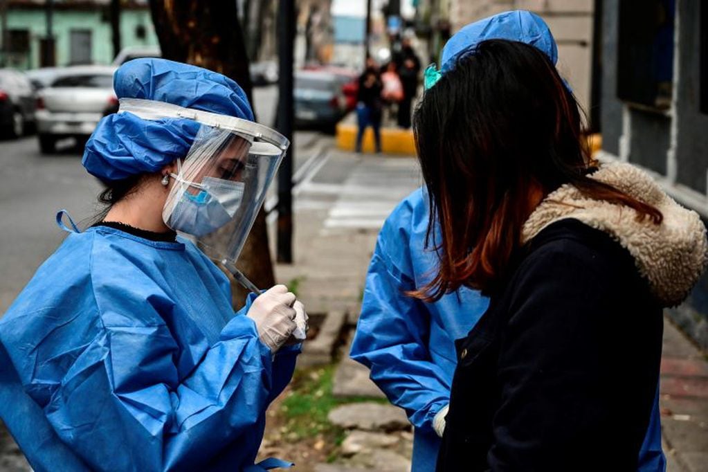 Argentinian dentist Agostina Guerra (L), who graduated from the University of Buenos Aires (UBA), is pictured working as a volunteer to detect cases of the COVID-19 coronavirus, in La Boca neighborhood, Buenos Aires, on August 3, 2020. - A group of volunteers of the University of Buenos Aires (UBA) is dedicated to look for coronavirus-infected people. (Photo by RONALDO SCHEMIDT / AFP)    hisopado casos del dia  hisopados test testeos en un colectivo  detectar