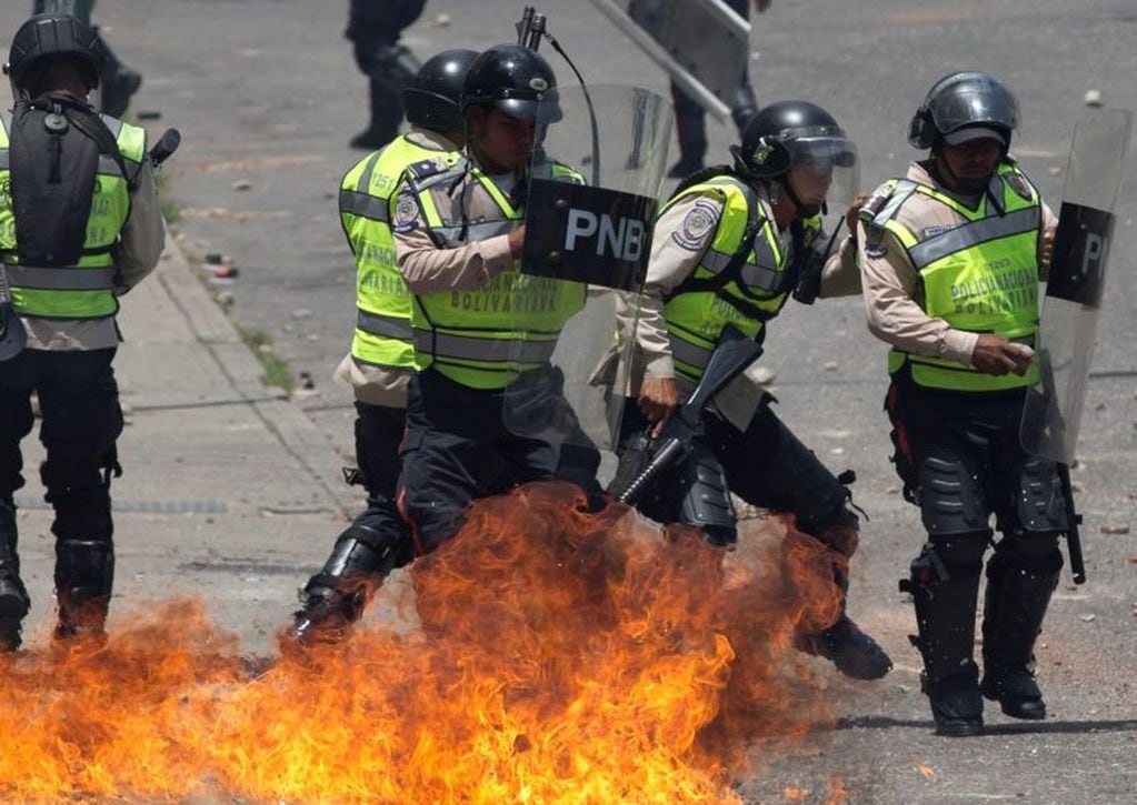 Bolivarian National Police officers move away after a gasoline bomb, launched by demonstrators, lands close during a protest in Caracas, Venezuela, Thursday, April 6, 2017. The South American country has seen near-daily protests since the Supreme Court issued a ruling nullifying congress last week. The court pulled that decision back after it came under heavy criticism, but opposition leaders said the attempt to invalidate a branch of power revealed the administration's true dictatorial nature. (AP Photo/Ariana Cubillos)