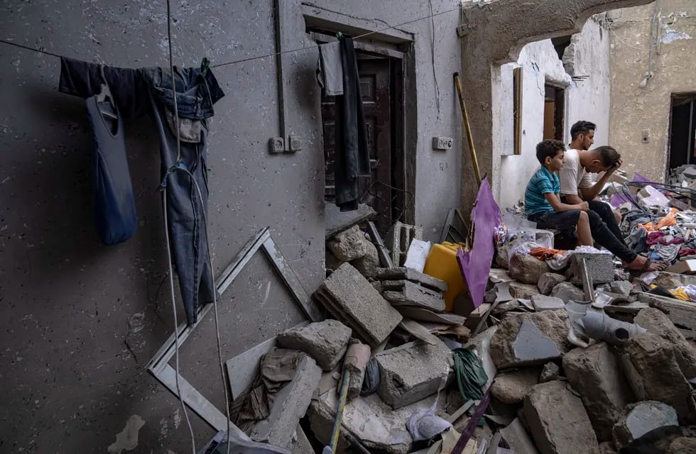 Palestinos sentados entre los escombros de una casa después de que fuera alcanzada por un bombardeo israelí en Khan Younis, en el sur de la Franja de Gaza, el domingo 29 de octubre de 2023.