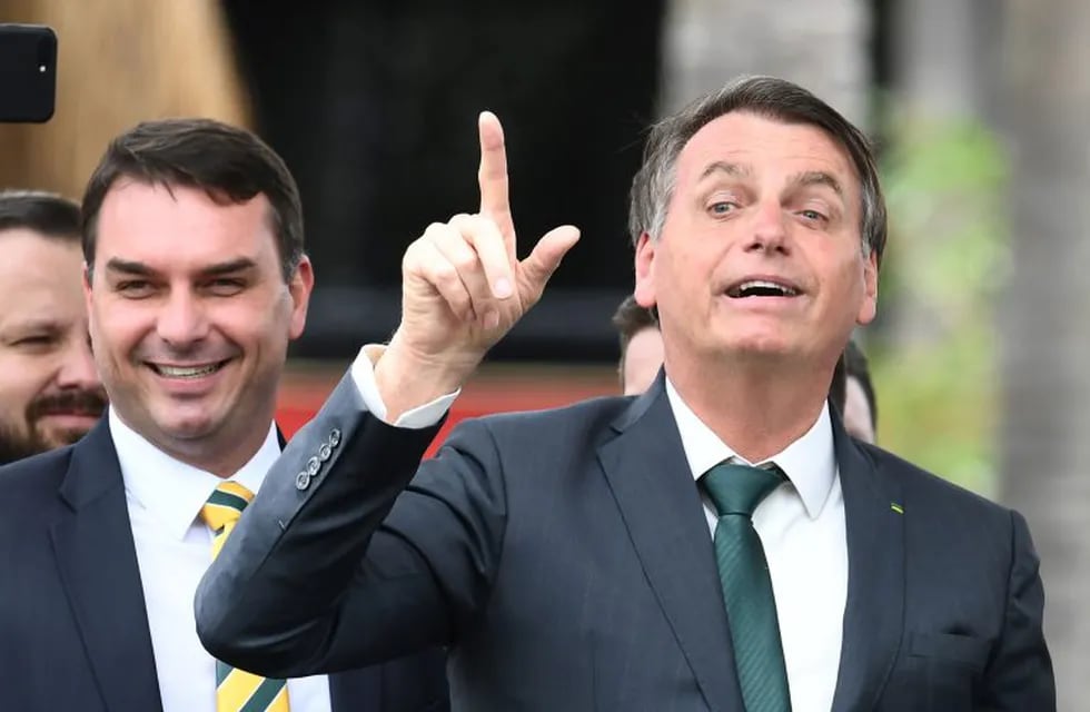 (FILES) In this file photo taken on November 21, 2019 Brazilian President Jair Bolsonaro (R) gestures next to his son, Senator Flavio Bolsonaro, during the launching of his new party, the Alliance for Brazil, at a hotel in Brasilia. - Press organizations in Brazil rejected a judge's decision on September 4, 2020 of prohibiting TV chain Globo the release of documents regarding Flavio Bolsonaro's judicial process for alleged corruption for considering it is under secrecy order. (Photo by EVARISTO SA / AFP)