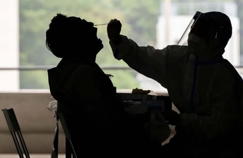 Una profesional de la salud le realiza un hisopado de coronavirus a un viajero. (AP)