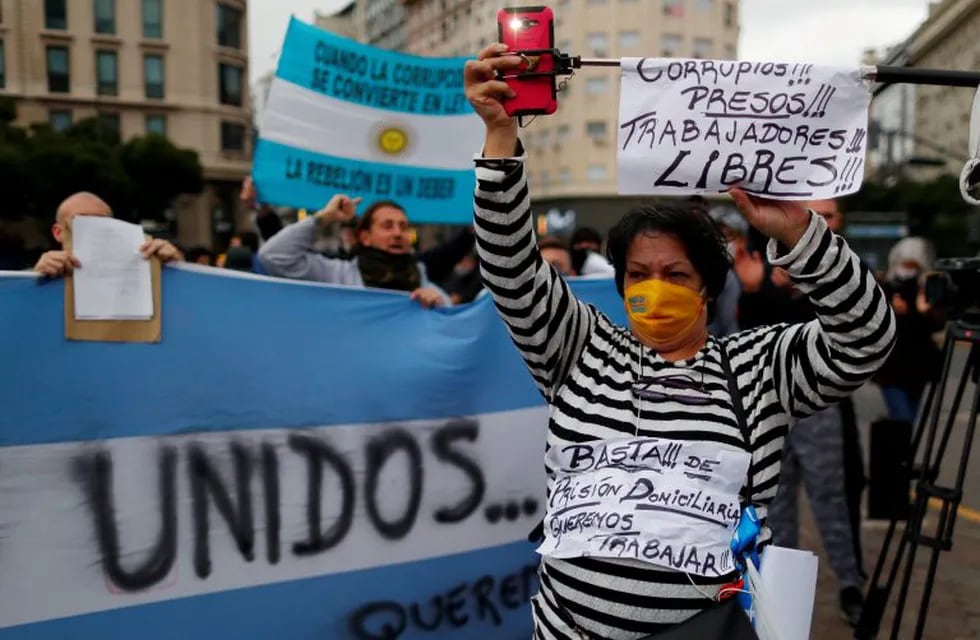 An anti-quarantine demonstrator wearing a prisoner's clothing holds a placard that reads \