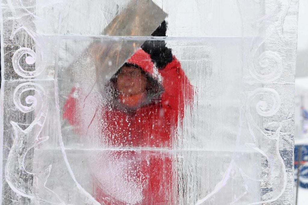 El escultor de hielo turco Ceyhun Konak trabaja su obra "Pawn's Dream"  (Foto de JEAN-PIERRE CLATOT / AFP)