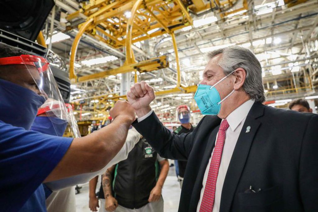 Handout picture released by Argentina's Presidency showing Argentine President Alberto Fernandez (R) greeting a worker of Volkswagen Argentina at the factory after it restarted production, in General Pacheco, Buenos Aires Province, on May 19, 2020 during the COVID-19 coronavirus pandemic. - Volkswagen Argentina restarted its production this week after Buenos Aires governor Axel Kicillof ordered a gradual opening of the quarantine and industrial activity to resume. Social isolation measures have been in place in Argentina since March 20, but some local and regional authorities were allowed to relax those, particularly in areas with few cases. (Photo by ESTEBAN COLLAZO / Argentinian Presidency / AFP) / RESTRICTED TO EDITORIAL USE - MANDATORY CREDIT "AFP PHOTO / ARGENTINA'S PRESIDENCY / ESTEBAN COLLAZO" - NO MARKETING - NO ADVERTISING CAMPAIGNS - DISTRIBUTED AS A SERVICE TO CLIENTS