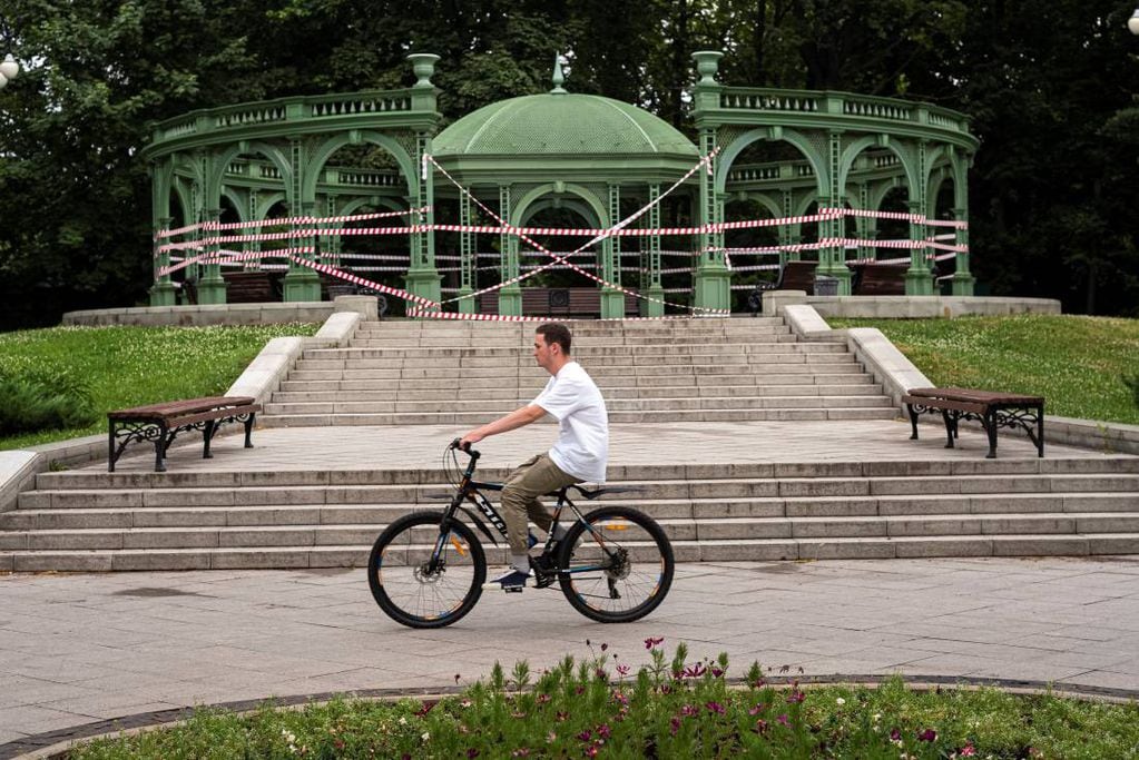 Un hombre pasea en bicicleta por delante de una pista de baile cerrada con cinta policial debido al coronavirus en un parque de Moscú, Rusia, el domingo 27 de junio de 2021. (Foto de Alexander Zemlianichenko/AP)