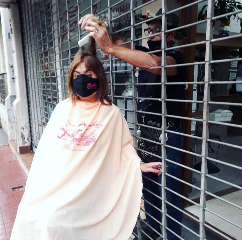 El peluquero rosarino Sergio corta detrás de las rejas del negocio