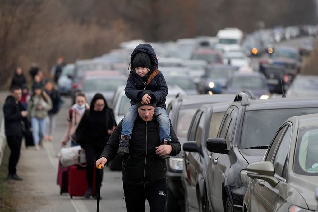 Refugiados ucranianos caminan junto a vehículos que se alinean para cruzar la frontera de Ucrania a Moldavia.