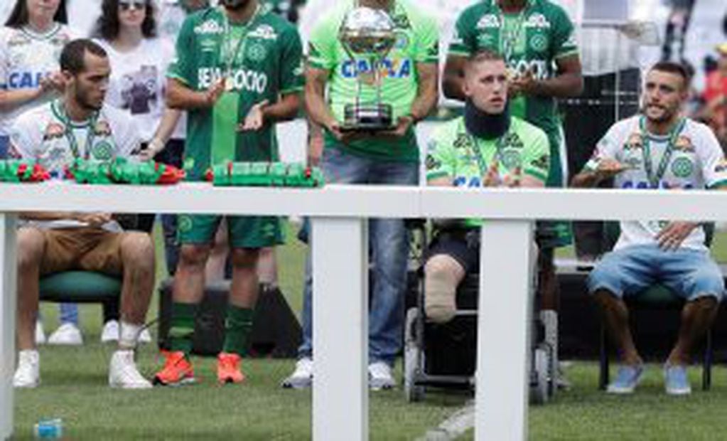 Chapecoense players Neto, left, goalkeeper Follmann, on the wheelchair, and Alan Ruschel, right, the three players that survived the air crash almost two months ago, attend a Sudamericana trophy award ceremony prior to a match against Palmeiras, in Chapec