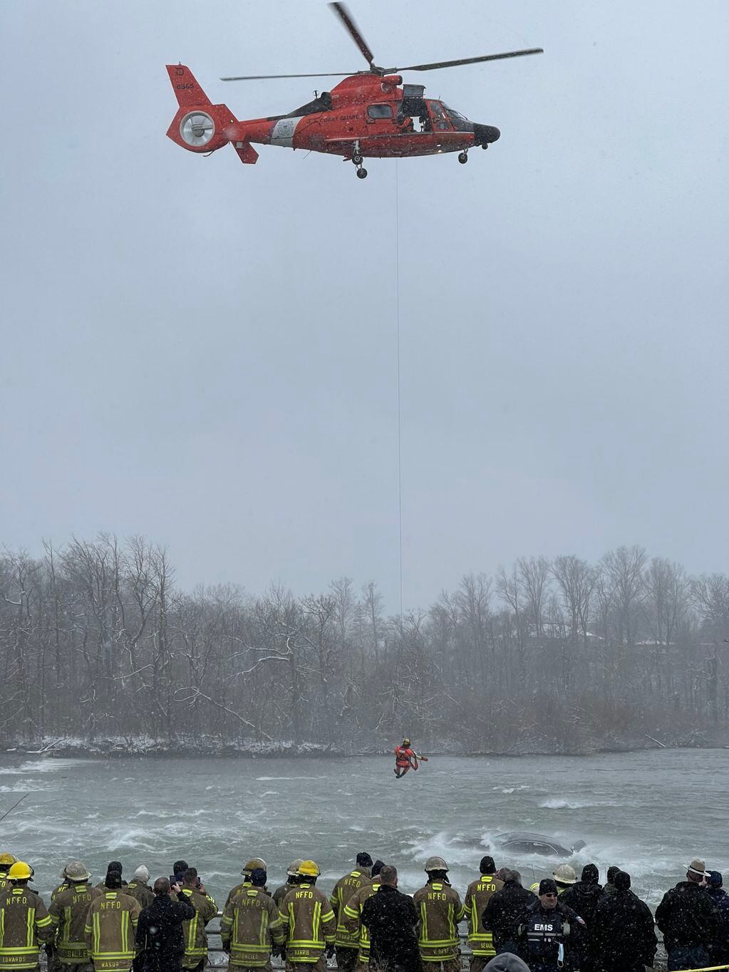 El helicóptero sosteniendo con un cable al rescatista que se acerca al auto para rescatar a la mujer dentro. Twitter @DigitalNewsQR