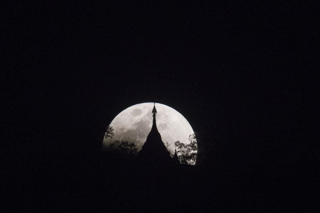The moon rises over a pagoda in Kumal, some 105 kms away from Mandalay City on January 31, 2018. 
Skywatchers were hoping for a rare lunar eclipse that combines three unusual events -- a blue moon, a super moon and a total eclipse -- which was to make for a large crimson moon viewable in many corners of the globe. / AFP PHOTO / YE AUNG THU
