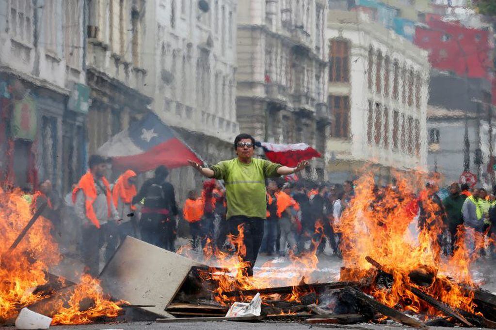 Un manifestante levanta la bandera chilena en una barricada en Valparaiso. (Reuters)